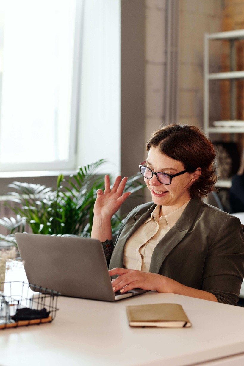 Woman waves at computer